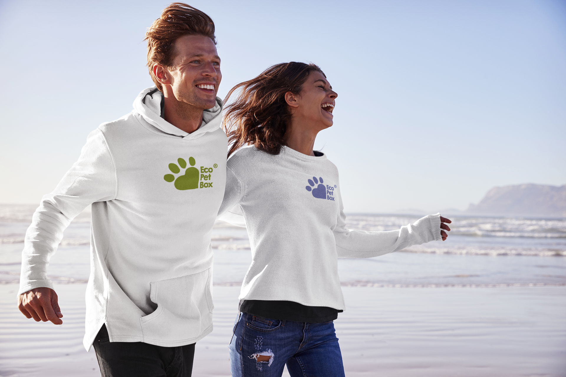 A couple running on the beach wearing EcoPetBox branded sweatshirts — carefree, active lifestyle